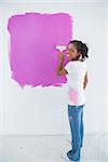 Happy woman painting her wall in bright pink and looking at camera