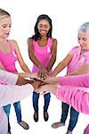 Happy women wearing pink and ribbons for breast cancer putting hands together on white background