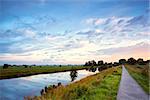 Dutch road for bicycles and river at dramatic sunrise