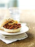 Barbeque Beef Sandwich with Caramelized Onions on Whole Wheat Bun, with Glass of Water in the Background