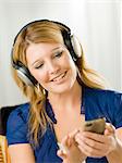 Mid adult woman wearing headphones and listening to mp3 player