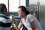 Young couple enjoying coffee in kitchen, smiling