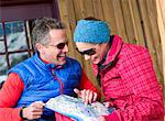 Mature man and young woman looking at map in ski resort