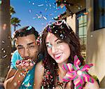Young couple blowing confetti and smiling, portrait