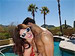 Young couple embracing at poolside, smiling