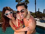 Young couple embracing at poolside, smiling