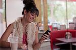 Young woman looking at mobile phone in diner