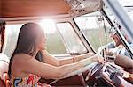 Young woman in camper van and smiling at boyfriend