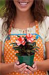 Young woman holding plant in garden centre, mid section