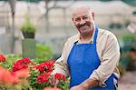 Mature man holding flowers in garden centre, smiling