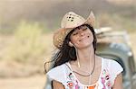 Young woman in cowboy hat wearing earphones, smiling