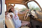 Young woman sitting in car on road trip, portrait