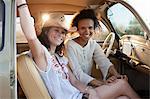 Young women sitting in car on road trip, portrait