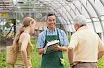 Mature sales assistant serving senior man and mid adult woman in garden centre