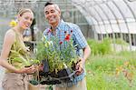 Mature man and mid adult woman shopping in garden centre, smiling