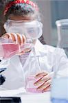 Girl pouring chemicals into conical flask