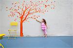 Girl pointing to orange tree mural on wall