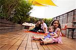 Girl with baby sister sitting on lap, parents in background