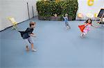 Boys and girl wearing superhero capes playing in back yard