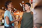 Young couple in vintage shop, woman trying on earrings