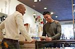 Young man buying item from shopkeeper in vintage shop