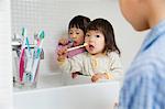Two girls brushing teeth at bathroom sink