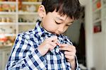 Close up portrait of young boy fastening shirt buttons