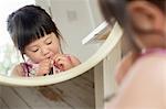 Mirror portrait of toddler fastening dress buttons