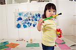 Female toddler holding paint bottle and brush