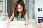 Young girl rolling out pastry on kitchen counter