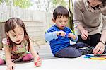 Mother and two children drawing in garden