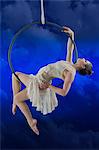 Aerialist performing on hoop against blue background