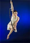 Aerialist poised on hoop against blue background