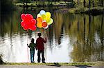 Brother and sister in front of lake with bunches of balloons