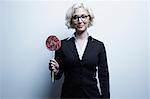 Studio portrait of blond businesswoman with red lollipop