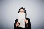 Studio portrait of businesswoman holding up newspaper