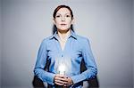 Studio portrait of young business woman holding lit lightbulb