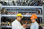 Two warehouse workers looking at copper pipe