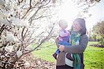 Portrait of baby girl and grandmother next to magnolia blossom