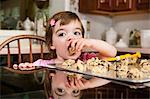 Close up portrait of young female toddler eating currant cakes