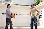 Father holding basketball with adult son