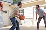 Father and adult son playing basketball