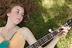 Teenage girl playing banjo on grass, overhead view