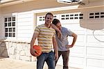 Father leaning on adult son's shoulder with basketball