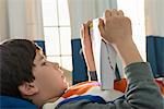 Boy lying on bed reading book