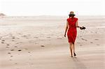 Mature woman wearing red dress walking on beach