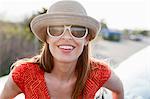 Mature woman wearing sunglasses and sunhat smiling towards camera