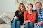 Portrait of mother and father with teenage daughter on sofa