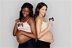 Two pregnant women holding ultrasound scans