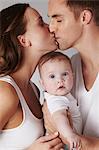 Mother and father kissing, with baby daughter